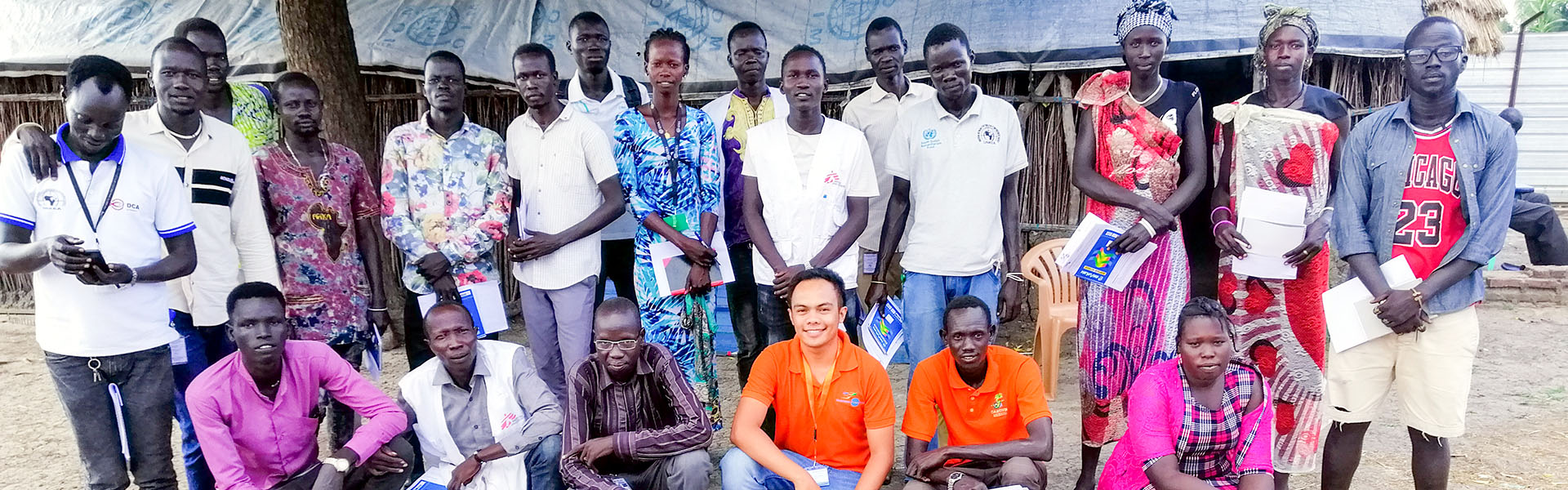 Nohman with local peacebuilders in South Sudan outside and posing for picture