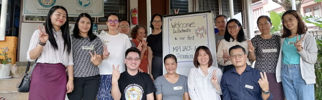 MPI Lao Alumni with MPI's Research, Documentation, and Learning Team posing for group picture in front of a welcome sign.